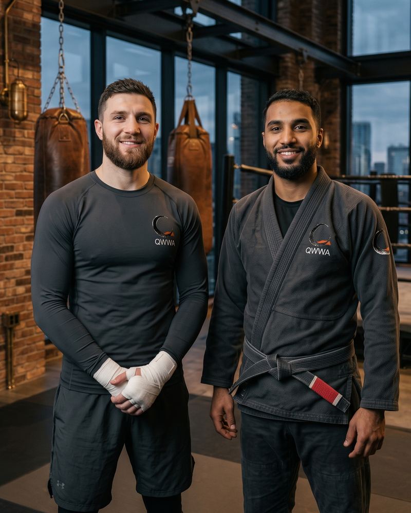 Two brothers in a rash guard and a gi, standing in a boxing gym